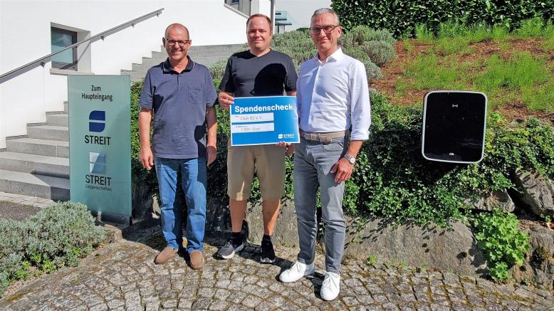 Vorsitzender Club 82 und Geschäftsführer Streit Software stehen vor dem Eingang von Streit Software und halten ein Spendenschild 1.000 € in der Hand