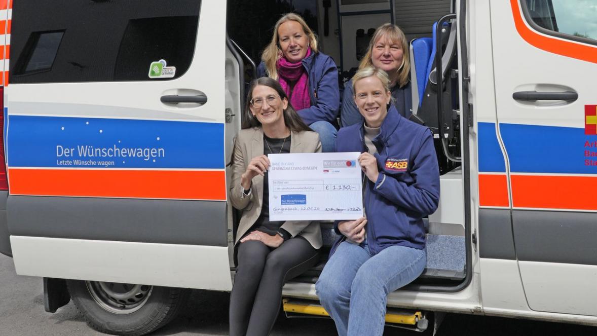 Dunja Bruckner (BENZ), Beate Schwab (Club 82), Sandra Wolf (ASB) und Corinna Oberle (ASB) sitzen im Wünschewagen und zeigen den Spendenscheck