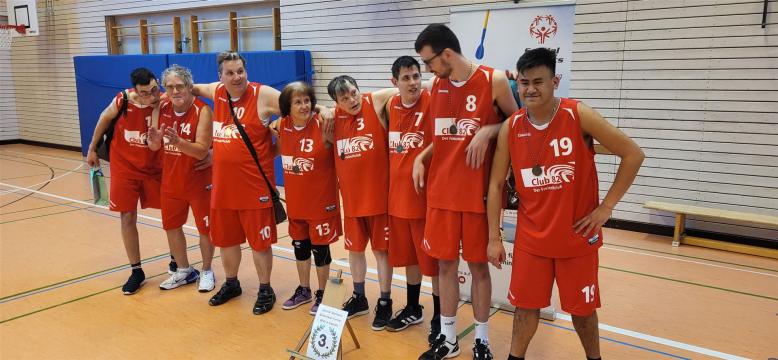 8 Basketball Spieler des Club 82 stehen als Gruppe zusammen. Alle tragen das rote Team-Trikot.