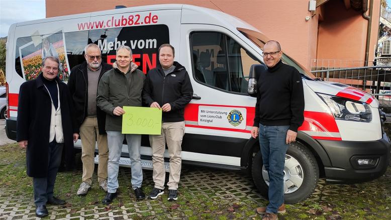 Vorsitzender und Geschäftsfüherer des Club 82 stehen mit 3 Vertretern des Lionsclub Kinzigtal vor dem neuen Kleinbus. Zwei Personen halten ein Spendenschild mit 3000 € in der Hand. 